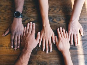 Multiple hands together on a table as peer support