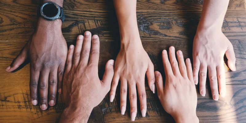 Multiple hands together on a table as peer support